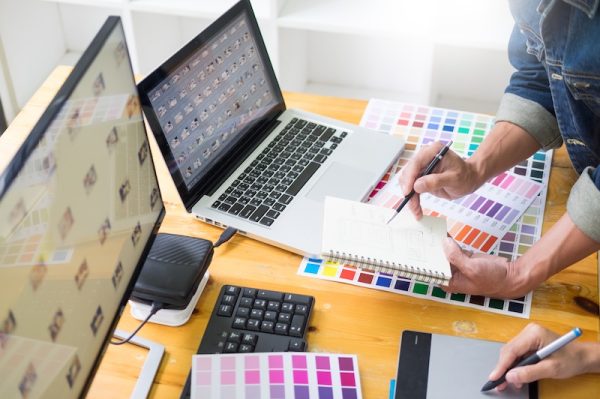 Deux graphistes travaillent avec deux ordinateurs et la palette de couleurs